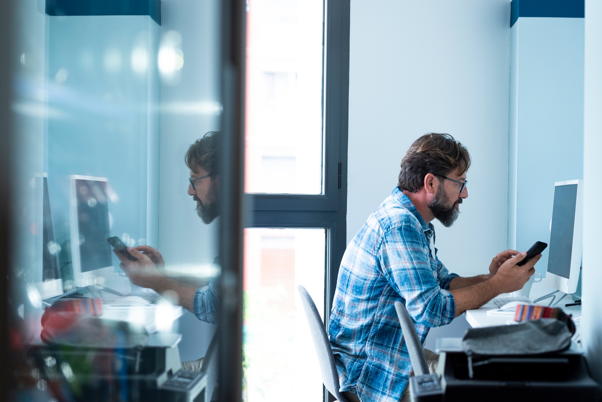 Adult business man work at office with mobile phone and desktop computer. Job and technology